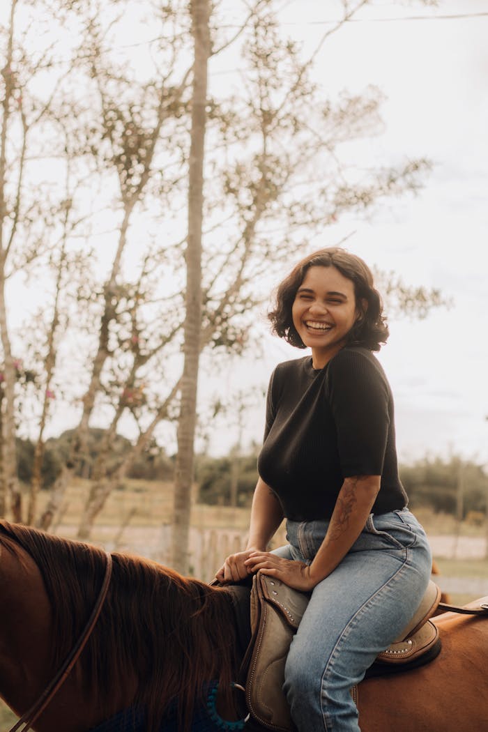 A cheerful woman enjoys horseback riding outdoors on a sunny day.
