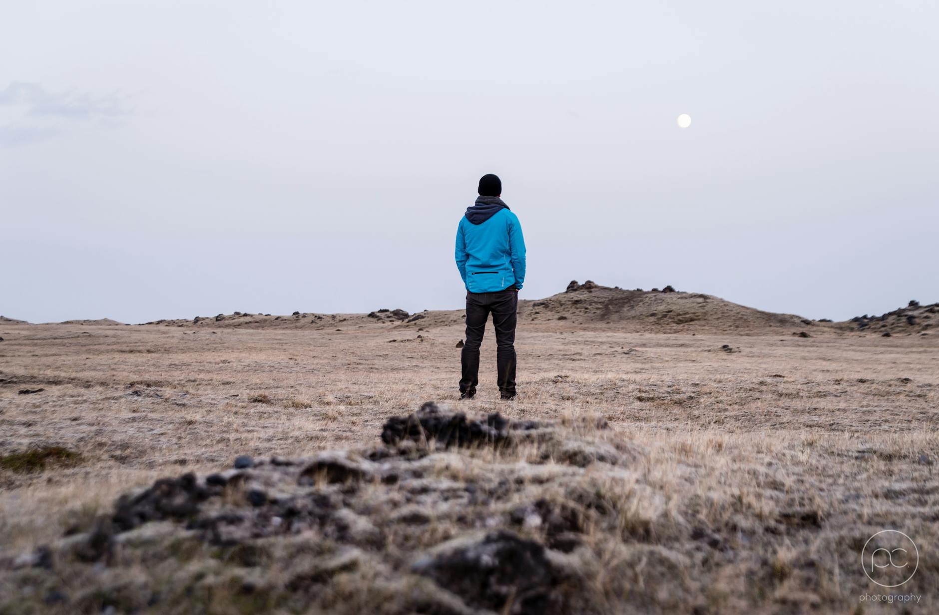 A lone hiker stands in a vast desert landscape under a full moon, capturing a sense of adventure and solitude.